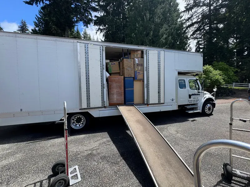A loaded Puget Sound Moving truck with the ramp down and furniture shrink-wrapped inside