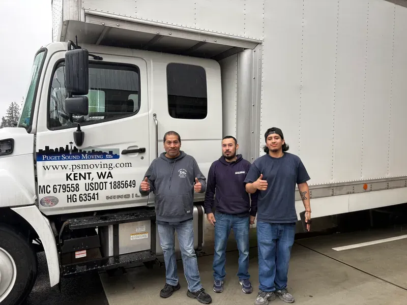 Three Puget Sound Moving crew members giving a thumbs up beside their truck